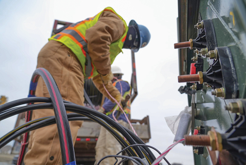 Workers pull underground line from the transformer to the pedestals that serve individual homes.