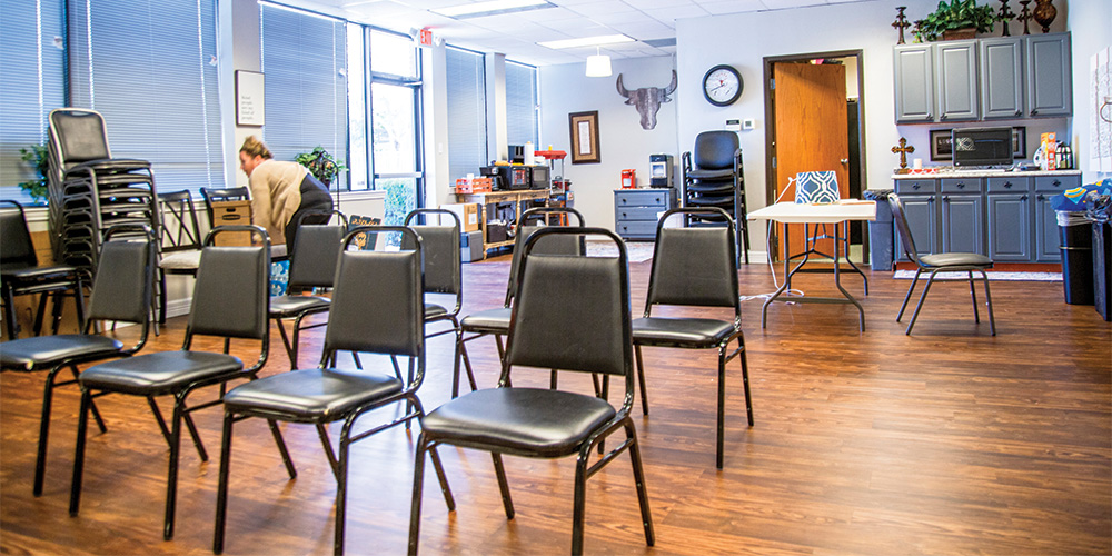 Kim Hughes sets up chairs for a group session later in the afternoon in the primary group meeting room.