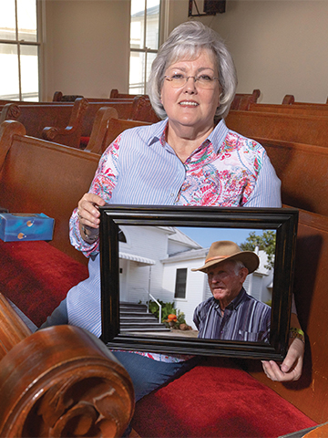 ABOVE: Becky Thomas poses with a photo of her uncle, Bob Grundy, who was a longtime church member and legendary high school coach and teacher. 
