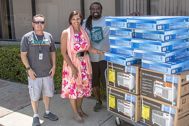 CoServ’s Energy Education Specialists Justin Porterfield and Alphonso Williams pose with the air conditioners and fans with Christian Community Action's Corporate Relations Manager Sandra Sims.
