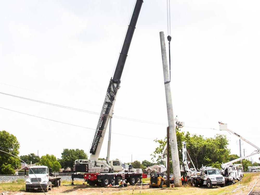 A crane lifts the concrete pole into position in Lewisville. The 18-foot hole was dug by CoServ's new digger truck. Photo by NICHOLAS SAKELARIS/CoServ