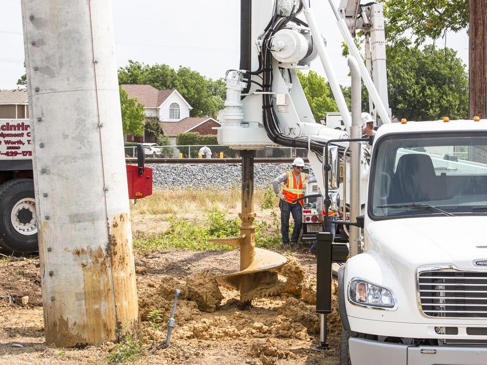 CoServ crews used the new Watson digging truck to dig an 18-foot hole for a concrete pole that crosses a railroad track in Lewisville. Here they shake off the dirt after digging. Photo by NICHOLAS SAKELARIS/CoServ