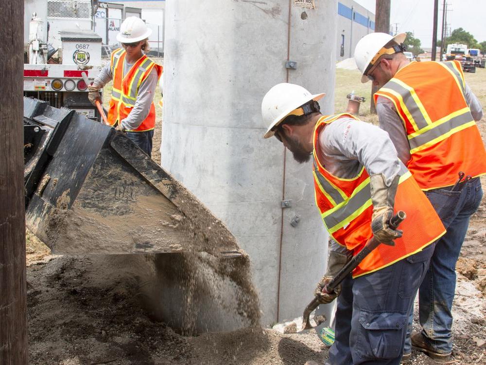 After placing the concrete pole, CoServ crews use gravel to fill in the hole. Photo by NICHOLAS SAKELARIS/CoServ