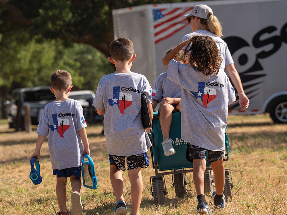 CoServ family members (left to right) Tripp Coulter, Corbitt Coulter and Gage Garza walk behind a wagon with Gabby Garza riding. Mother and lineman wife Sarah Garza pulls the wagon.