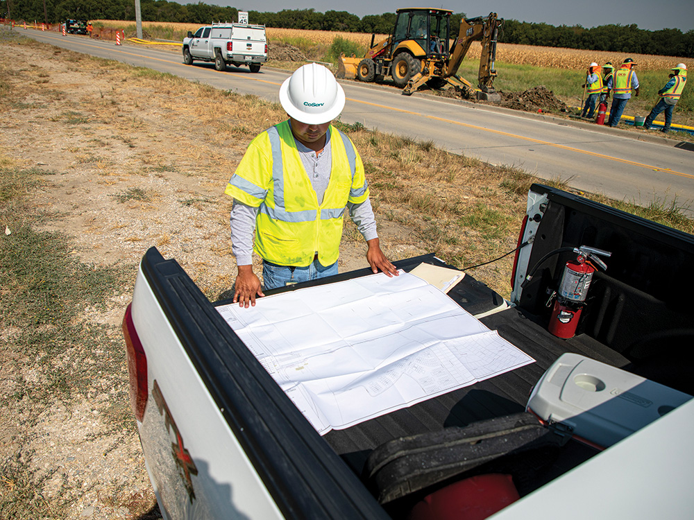 Felipe Puentes checks the plans while contractors dig a gas line on Frontier Parkway.