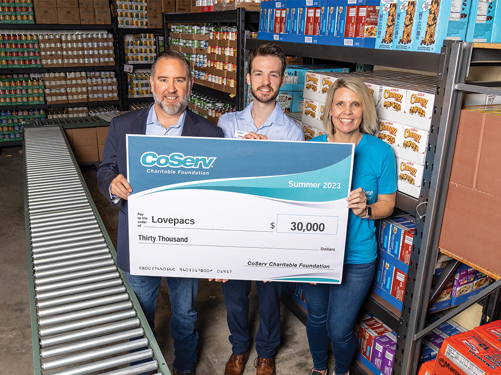 CoServ Charitable Foundation awarded a 30,000 grant to Lovepacs for food products to serve to school children in need. CoServ Community Event Specialist Walker Sims, District 3 Director Chris McCraw present a check to Lovepacs Executive Director Autumn Chavez in Frisco.
