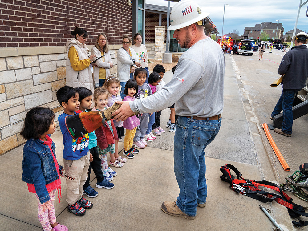 CoServ lineman Ethan Scheffler does a show and tell with students at Calhoun Early Childhood School.