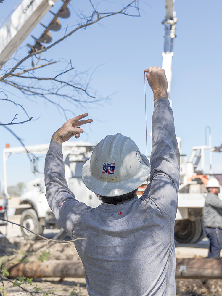 Linemen double check that a new pole is put up straight along the future extension of Panther Creek Parkway in Frisco.