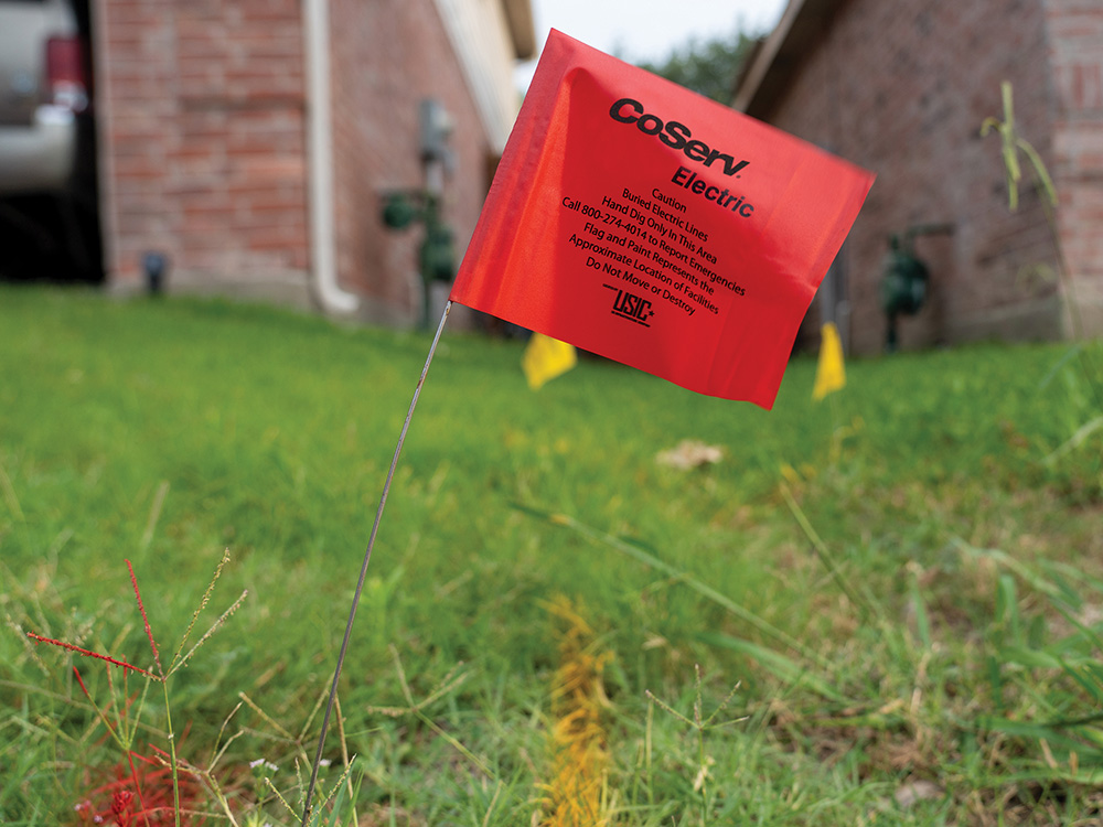 Flag used place by USIC to mark CoServ Electric lines during digging in a yard while new fiber lines were being laid in Mckinney.