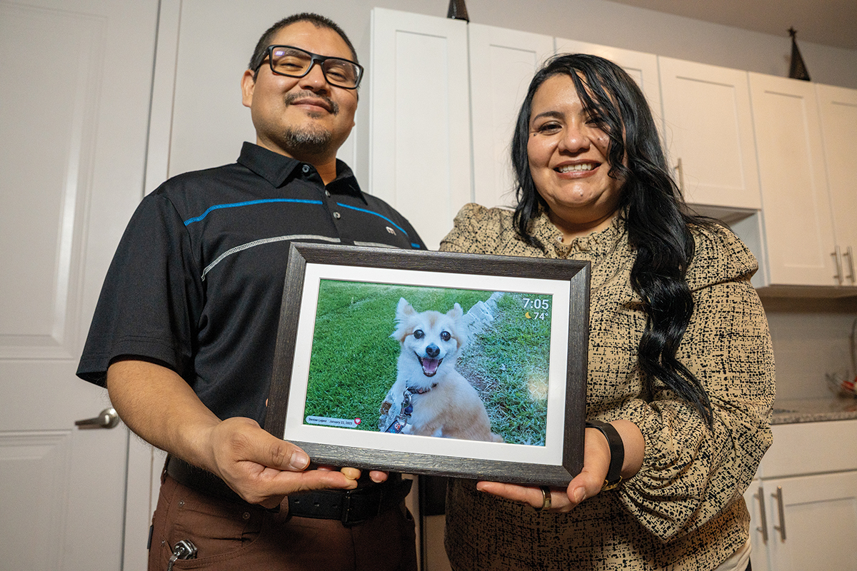 Ricardo Pena and Denys Lopez with a photo of their late dog Nikki, who passed after an illness. CoServ helped Ricard and Denys with a payment plan during their difficult time. Photo by BRIAN ELLEDGE