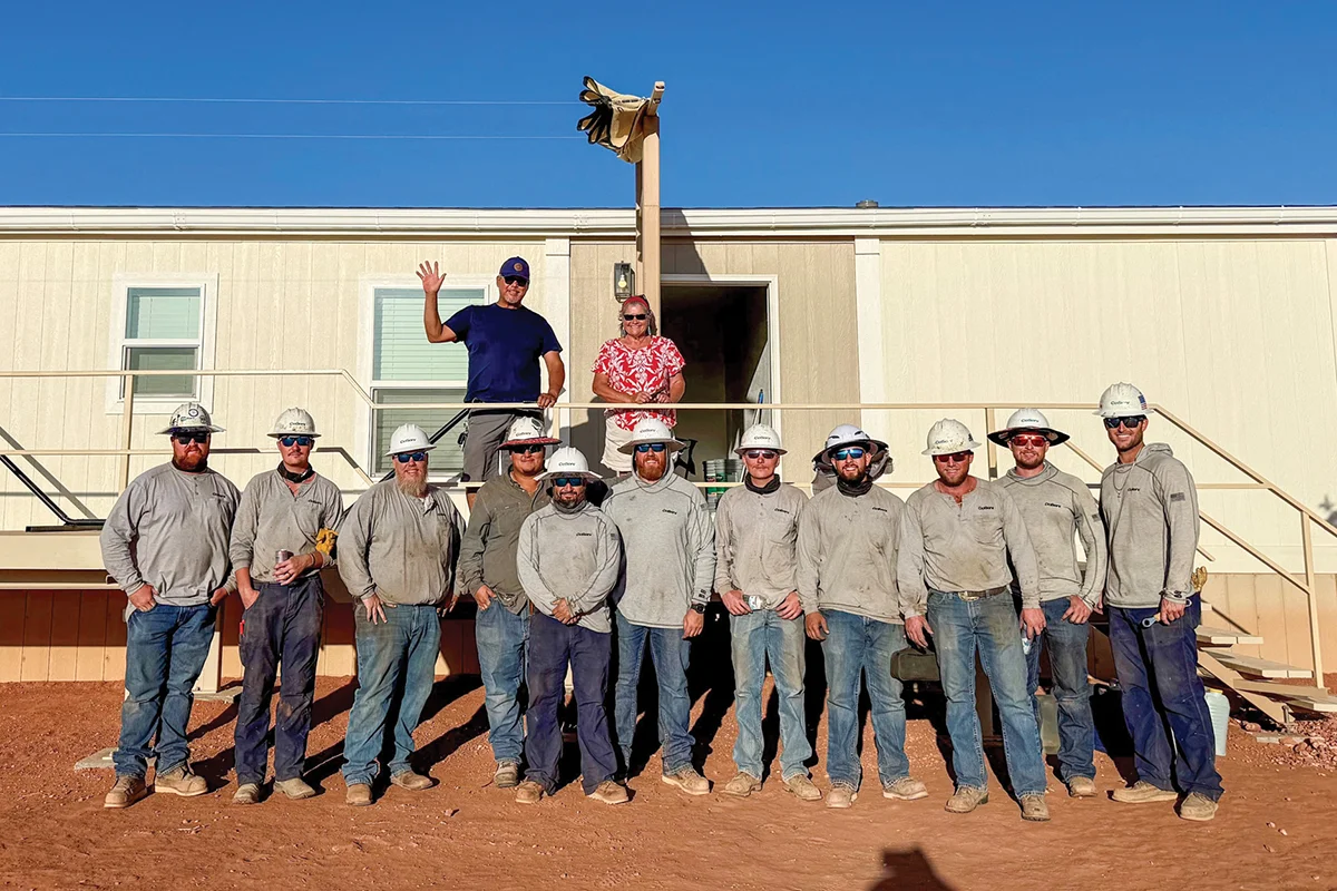 A CoServ Crew stands with one of the Navajo residents whom they brought power to.