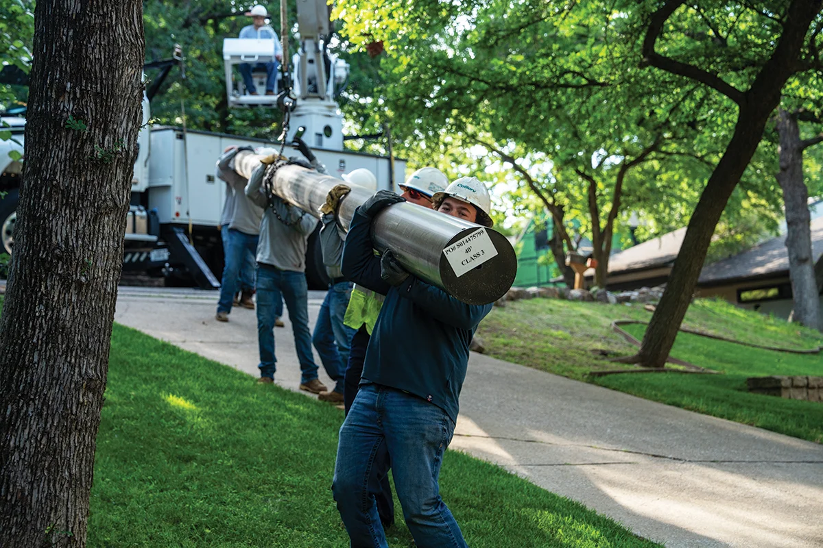 CoServ linemen carry a 400+ lbs. carbon fiber pole during a system upgrade project in Highland Village. Photo by BRIAN ELLEDGE