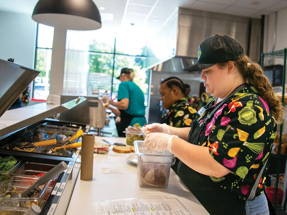 Danielle Bailey and Kalyn Bradley prepare food after the grand opening for the Hugs Café Headquarters in downtown McKinney.  Photo by NICHOLAS SAKELARIS