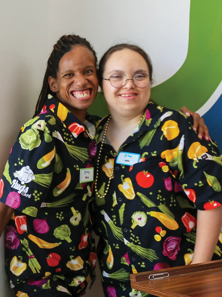 Hugs Cafe hostesses Marty Cole and Edith Jackson celebrate the grand opening July 2, 2026. The uniforms were purchased thanks to an Operation Roundup® grant from the CoServ Charitable Foundation. Photo by NICHOLAS SAKELARIS